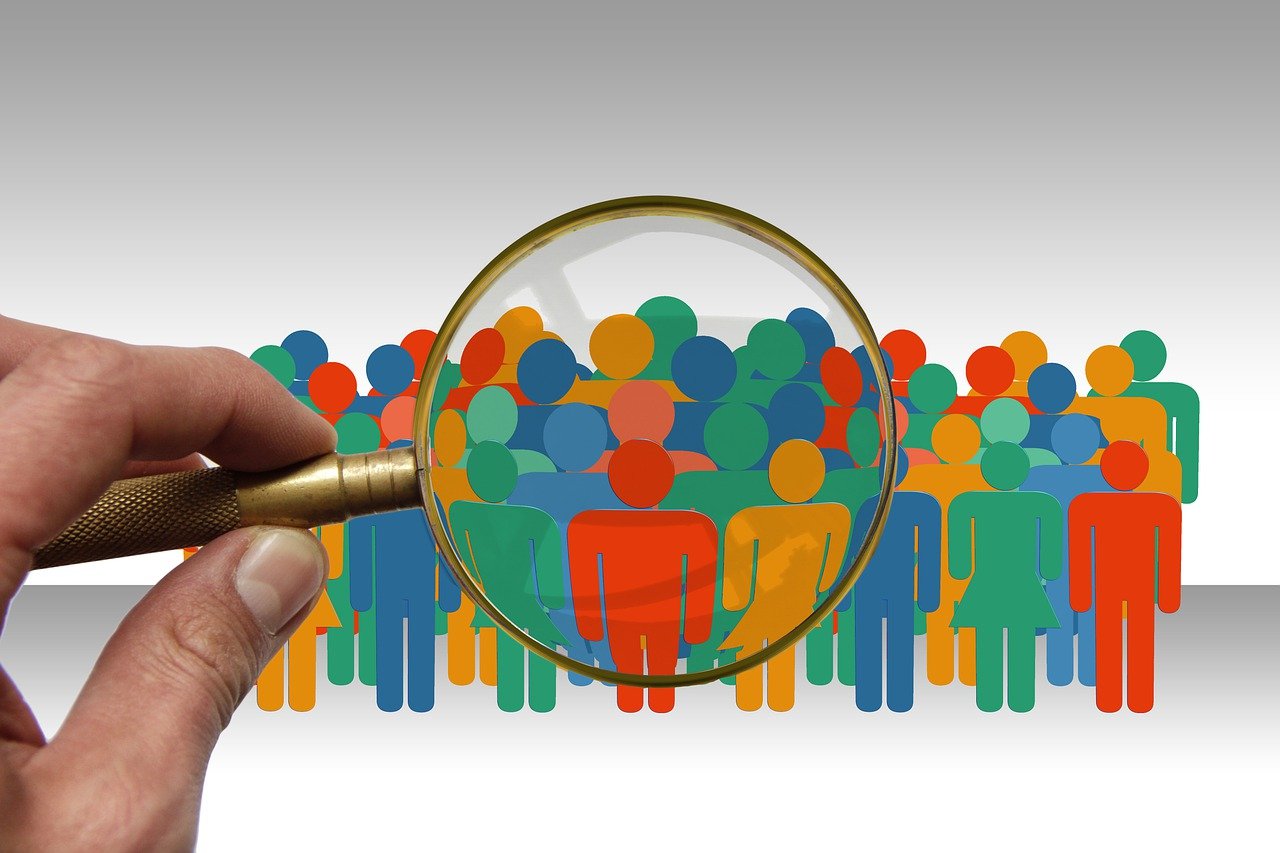 Diverse group of people under a magnifying glass representing the study of society in Sociology A-level.